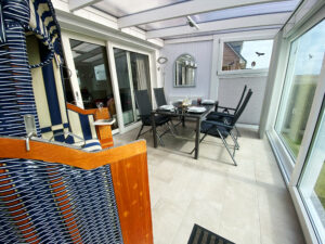 Strandkorb und ein gedeckter Esstisch im Wintergarten.